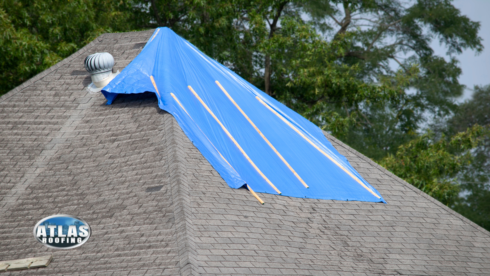 A blue tarp is covering the roof of a house.