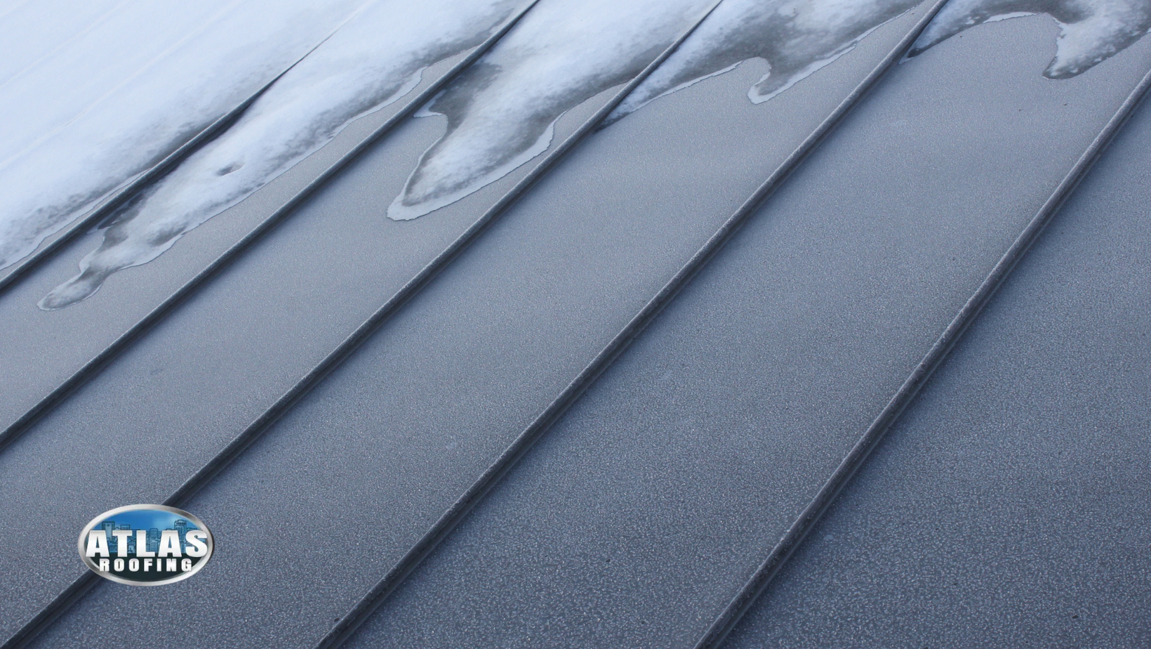 A close up of a gray roof with snow on it