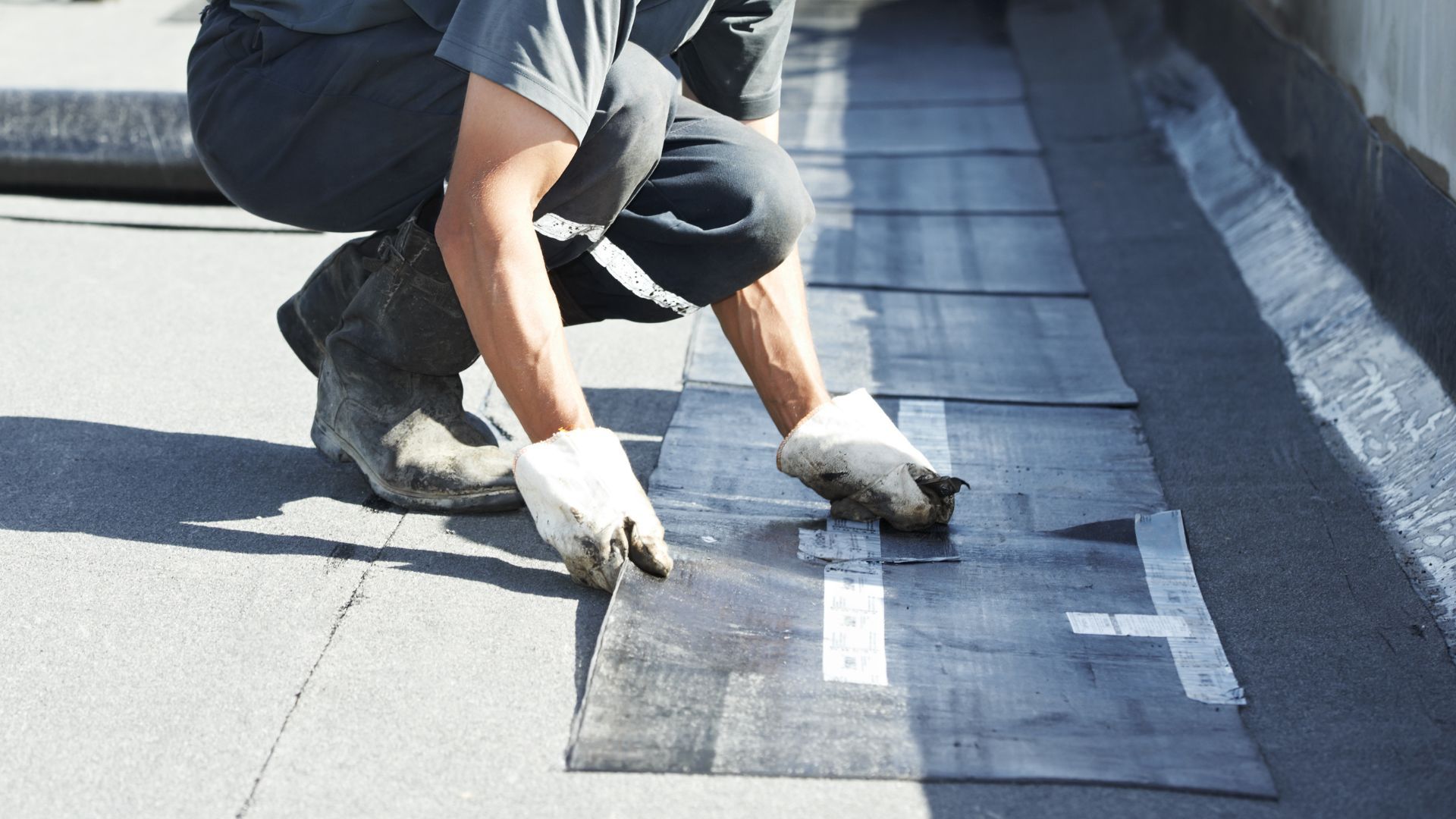 A man is working on a roof with a rubber mat.