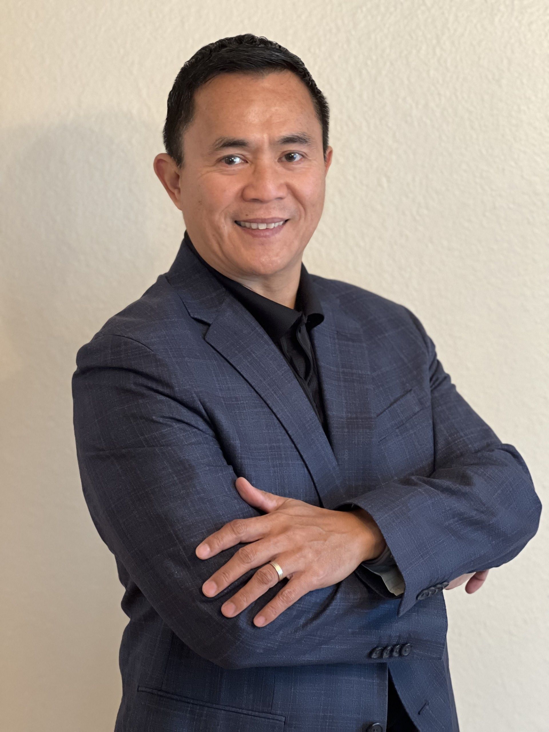 A woman is sitting at a desk with a laptop and a vase of flowers.