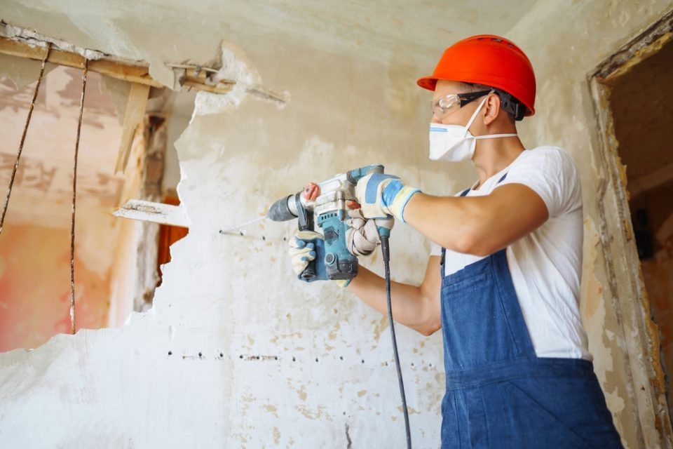A man is using a drill to drill a hole in a wall.