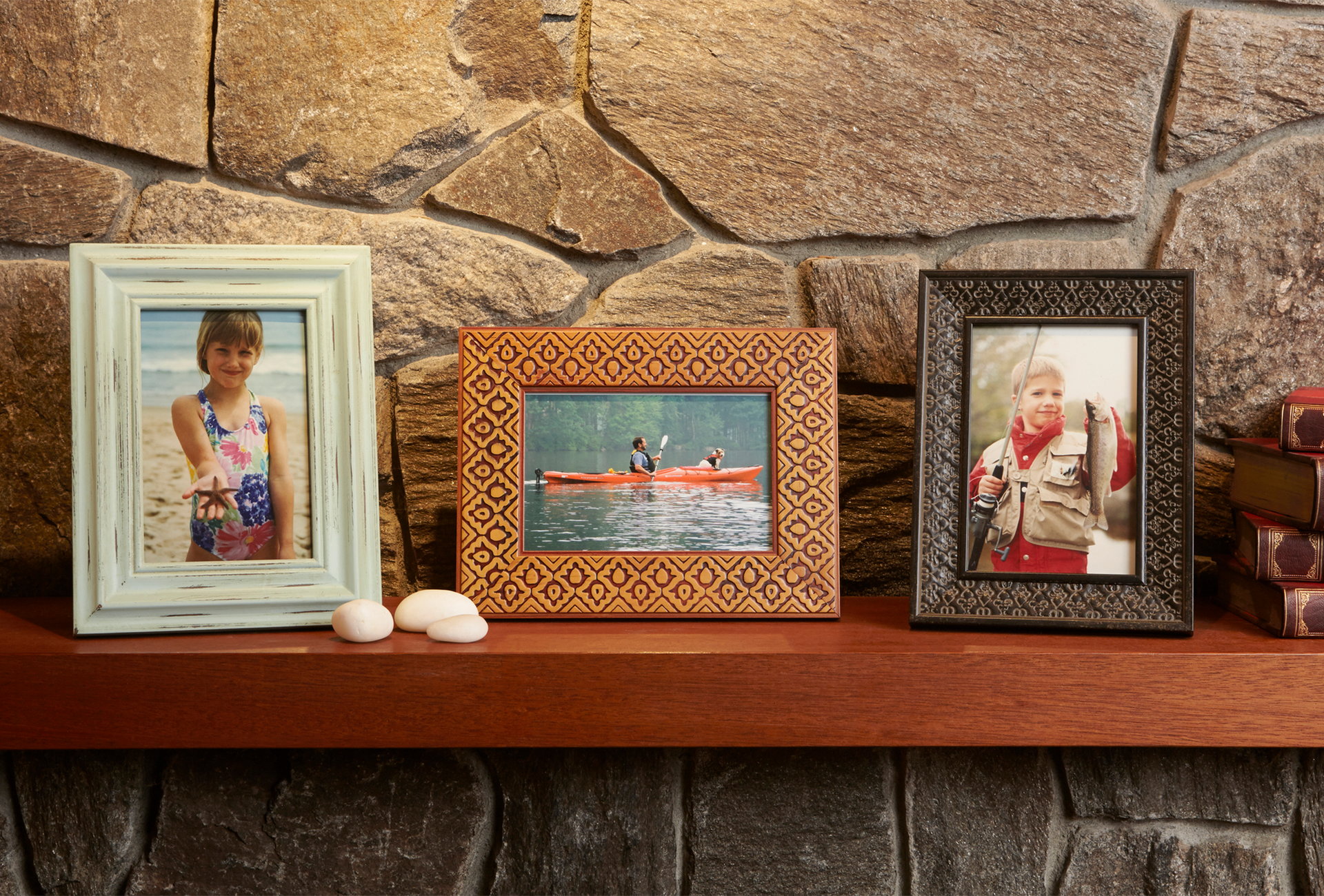 Three picture frames are sitting on a wooden shelf in front of a stone wall