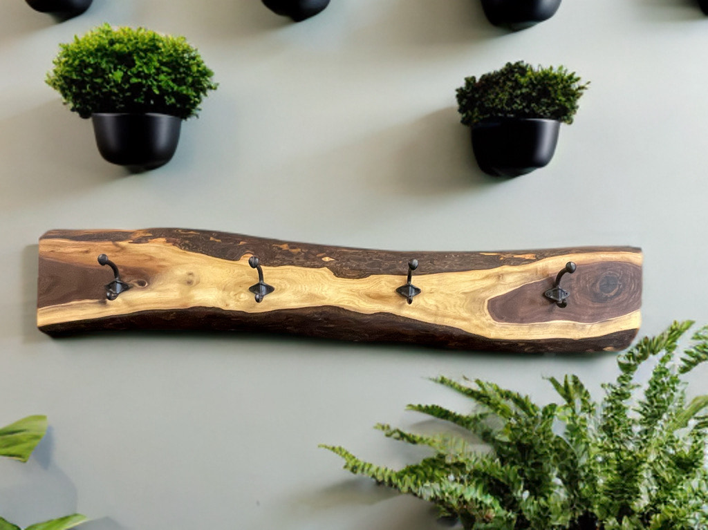 A wooden coat rack is hanging on a wall next to potted plants.
