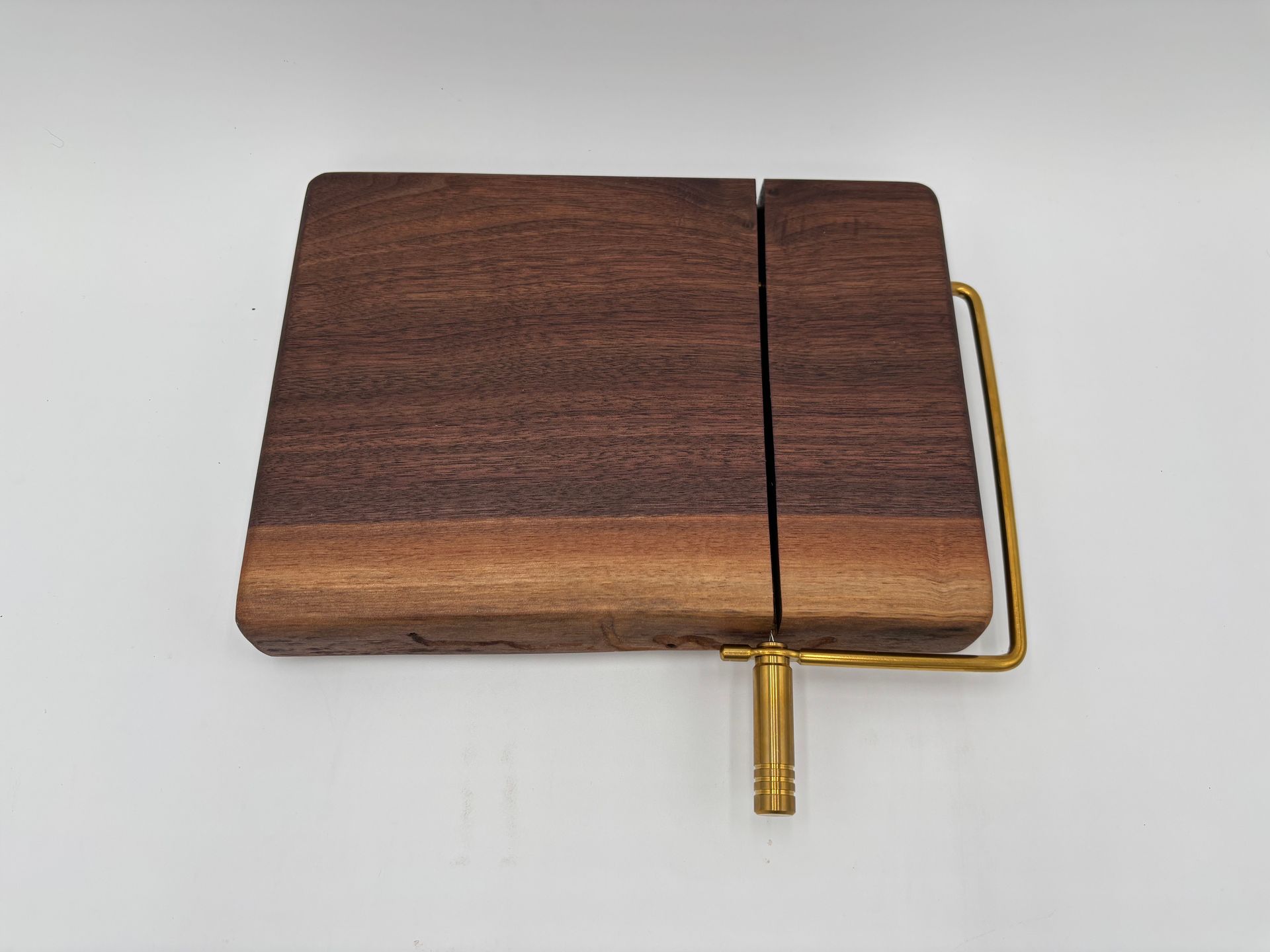 Wooden cheese slicer with gold-colored handle and base.