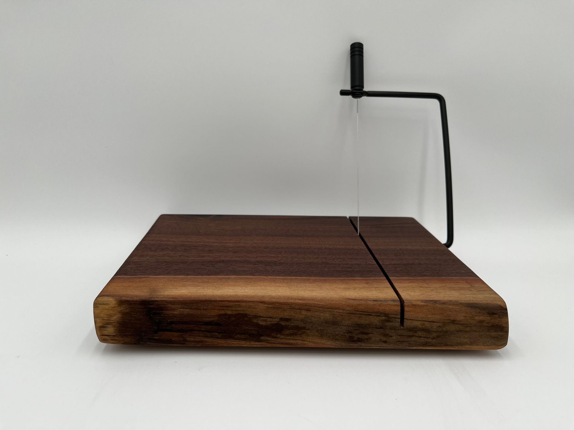 A wooden cutting board with a metal handle on top of it.