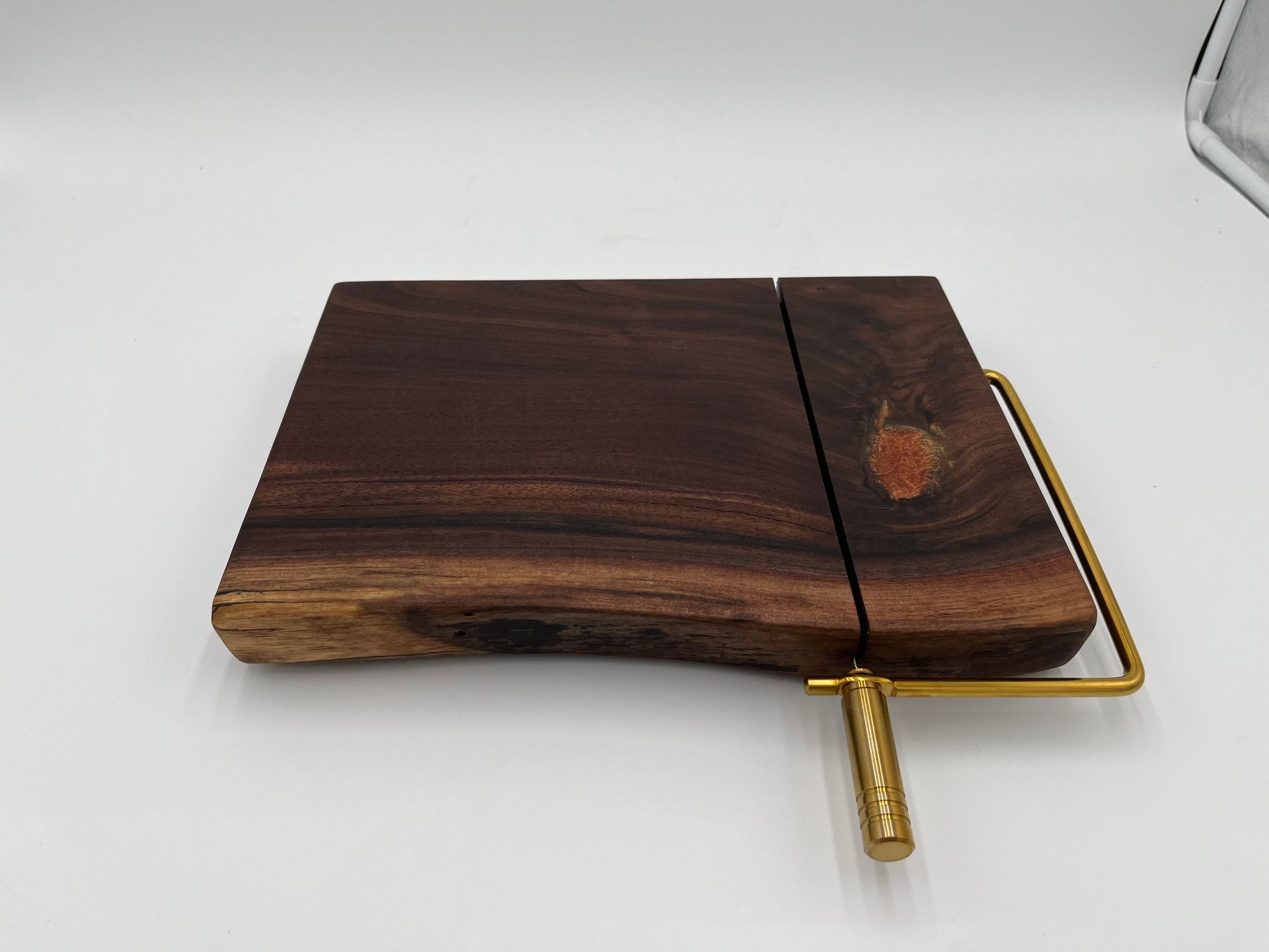 A wooden cutting board with a brass handle on a white surface.