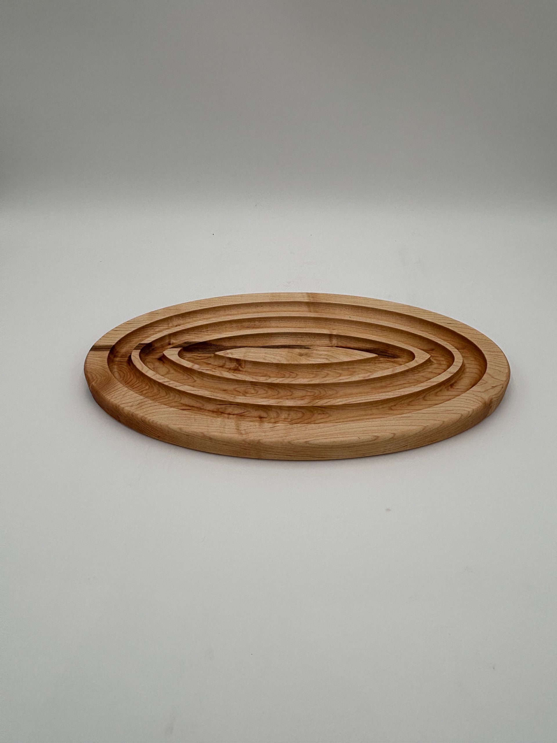 Wooden soap dish with concentric oval grooves, on a white background.