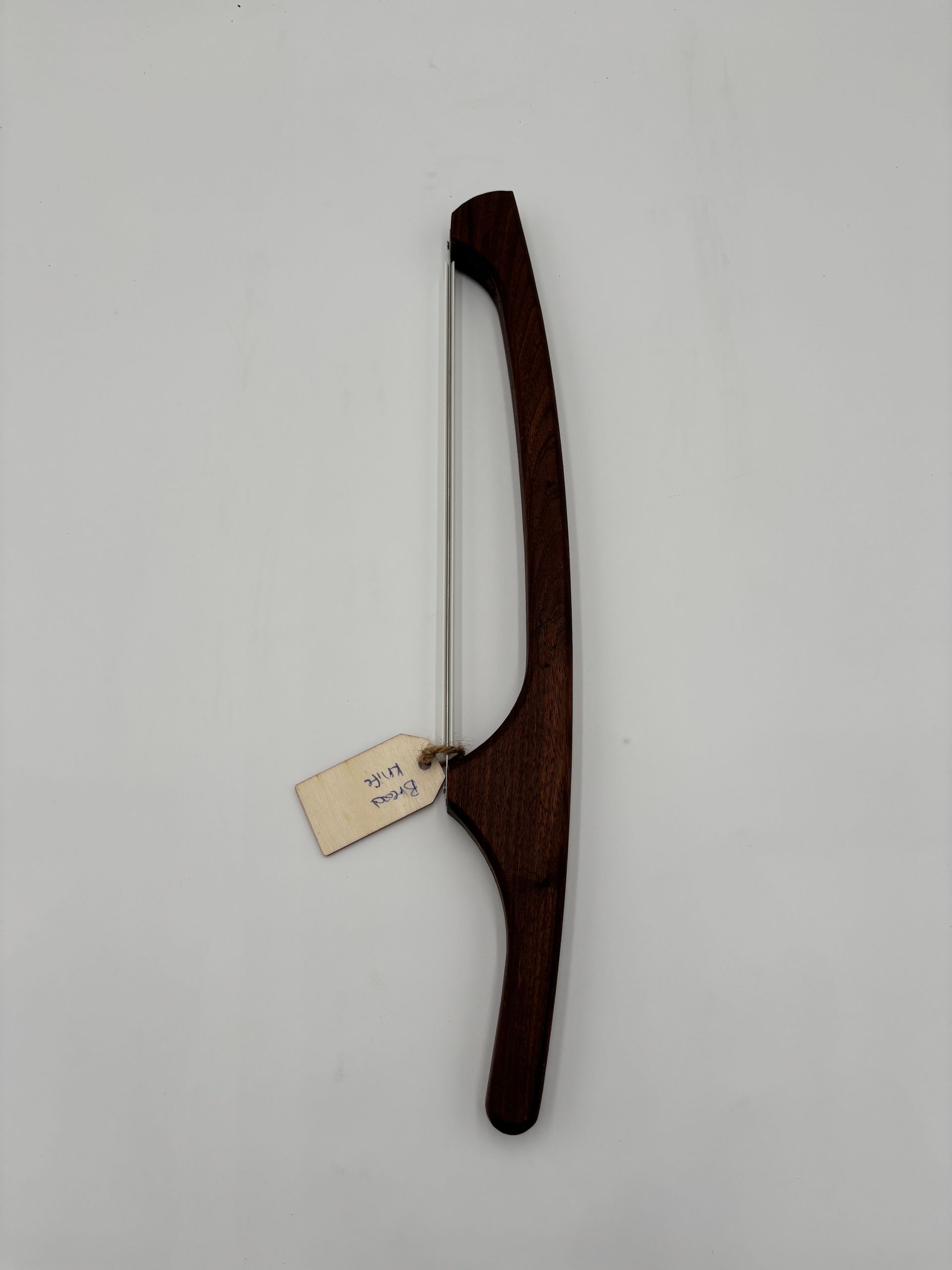 Brown wood coping saw with a silver blade and a small tag.