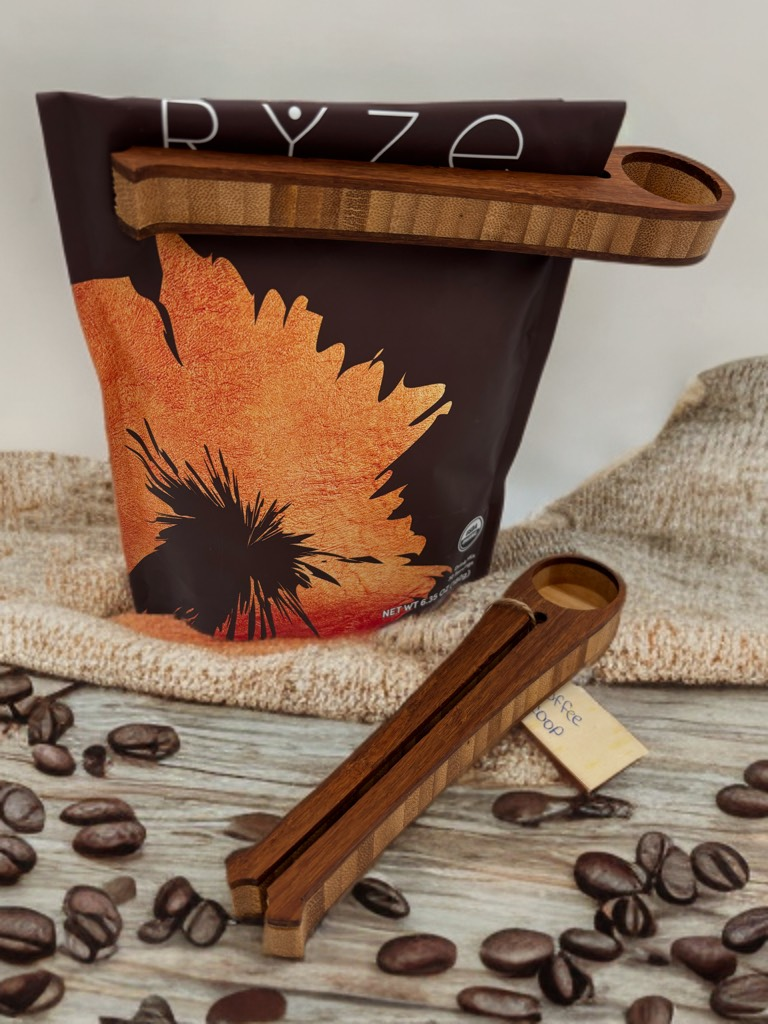 Two wooden bag clips holding a coffee bag, surrounded by beans.