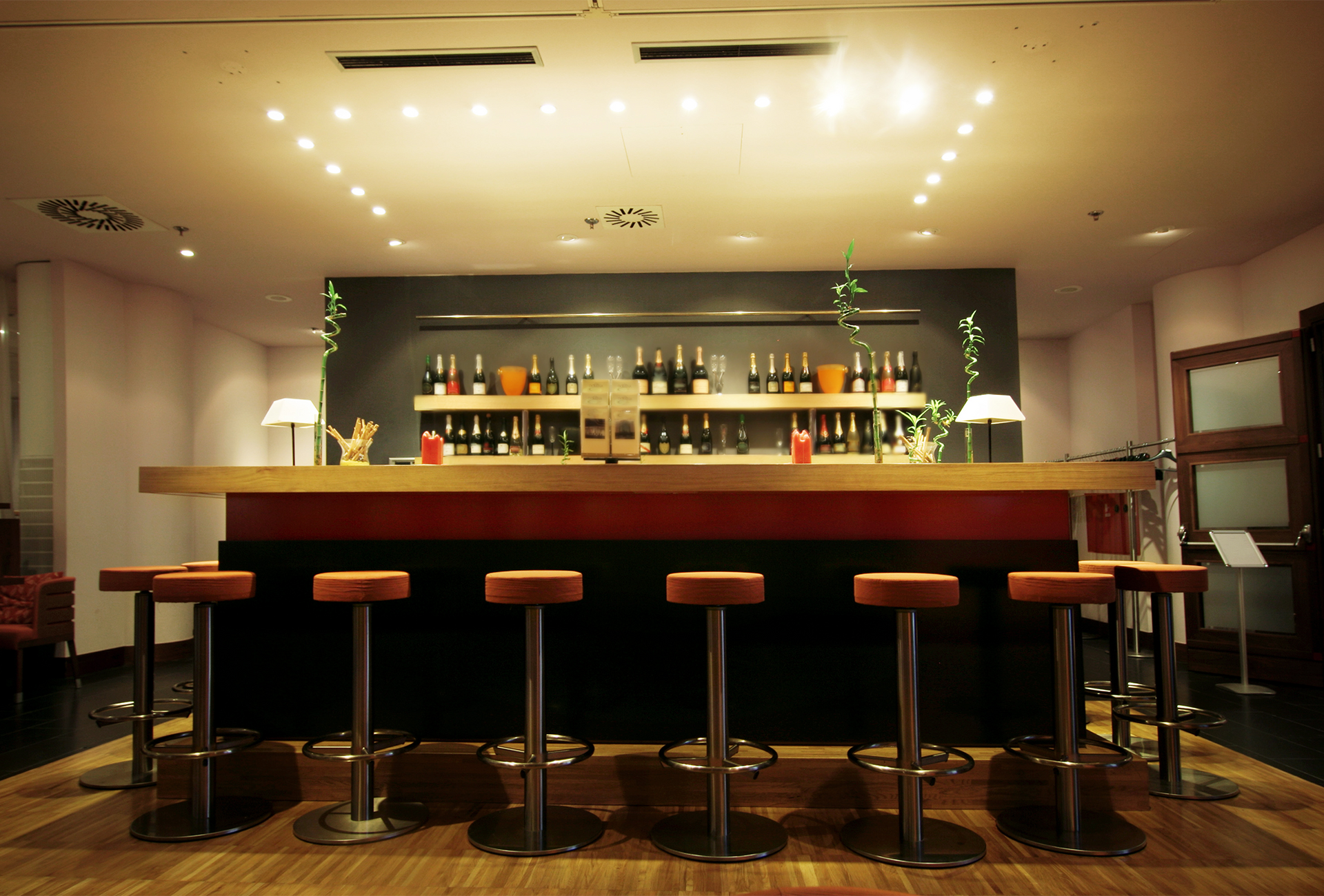 A bar with stools and bottles on shelves