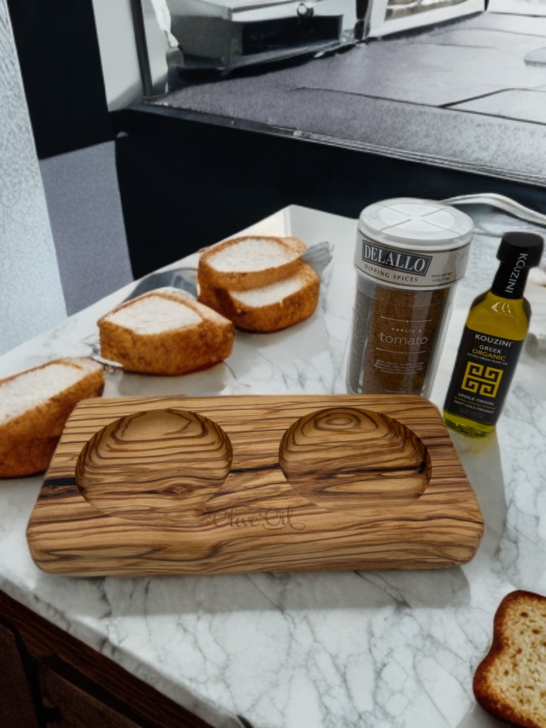 Wooden olive oil tray with bread, spices, and oil bottle on a marble countertop.