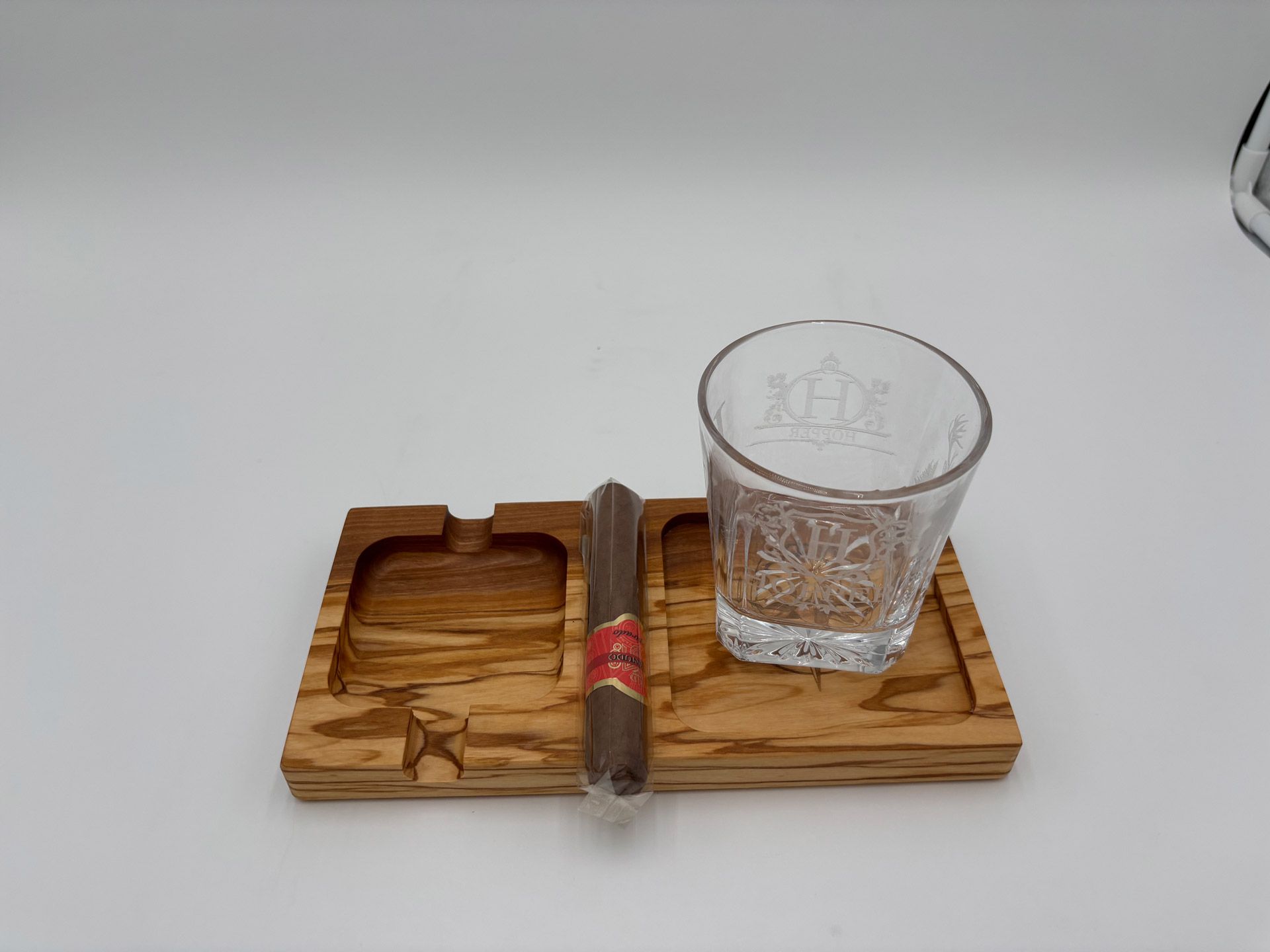 Wooden cigar ashtray with cigar and glass of water on a white background.