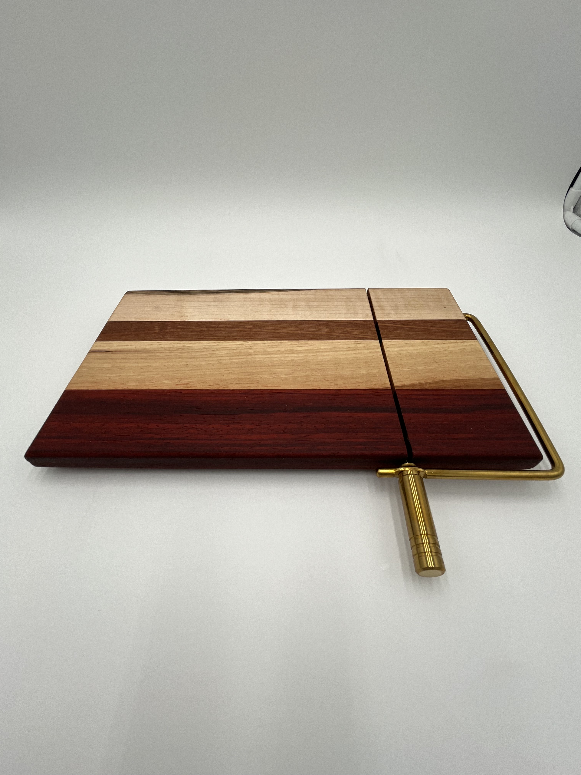 A wooden cutting board with a metal handle on a white surface.
