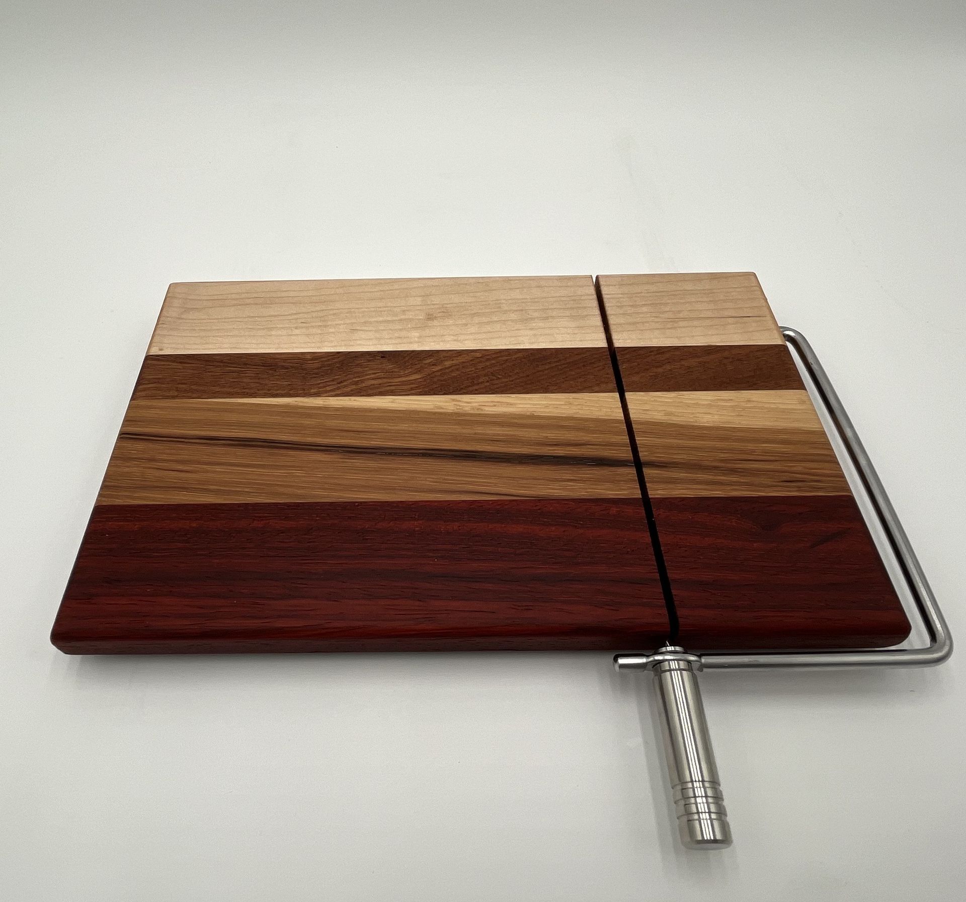 A wooden cutting board with a metal handle on a white surface.