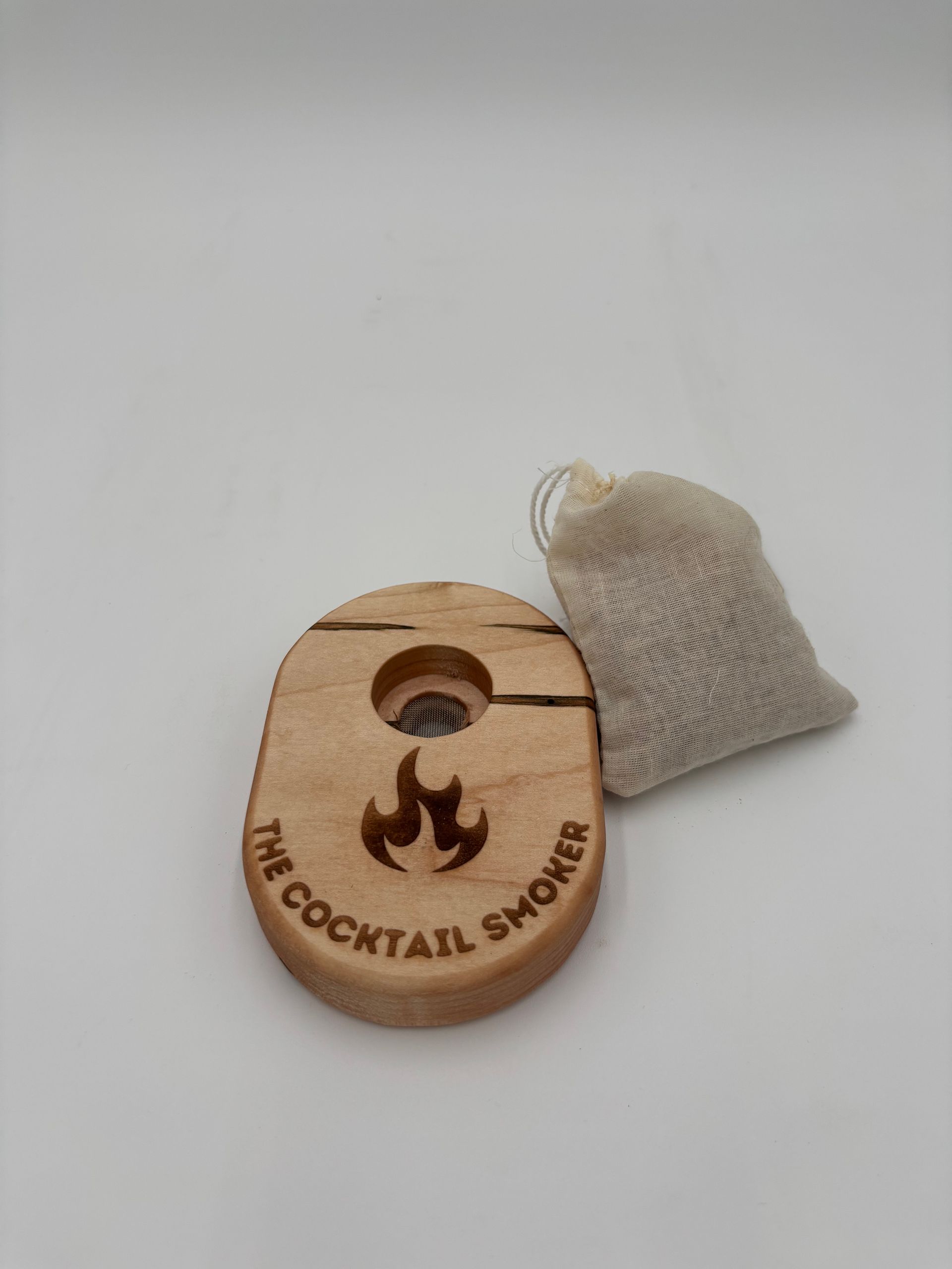 Wooden cocktail smoker with small bag of wood chips, on a white background.