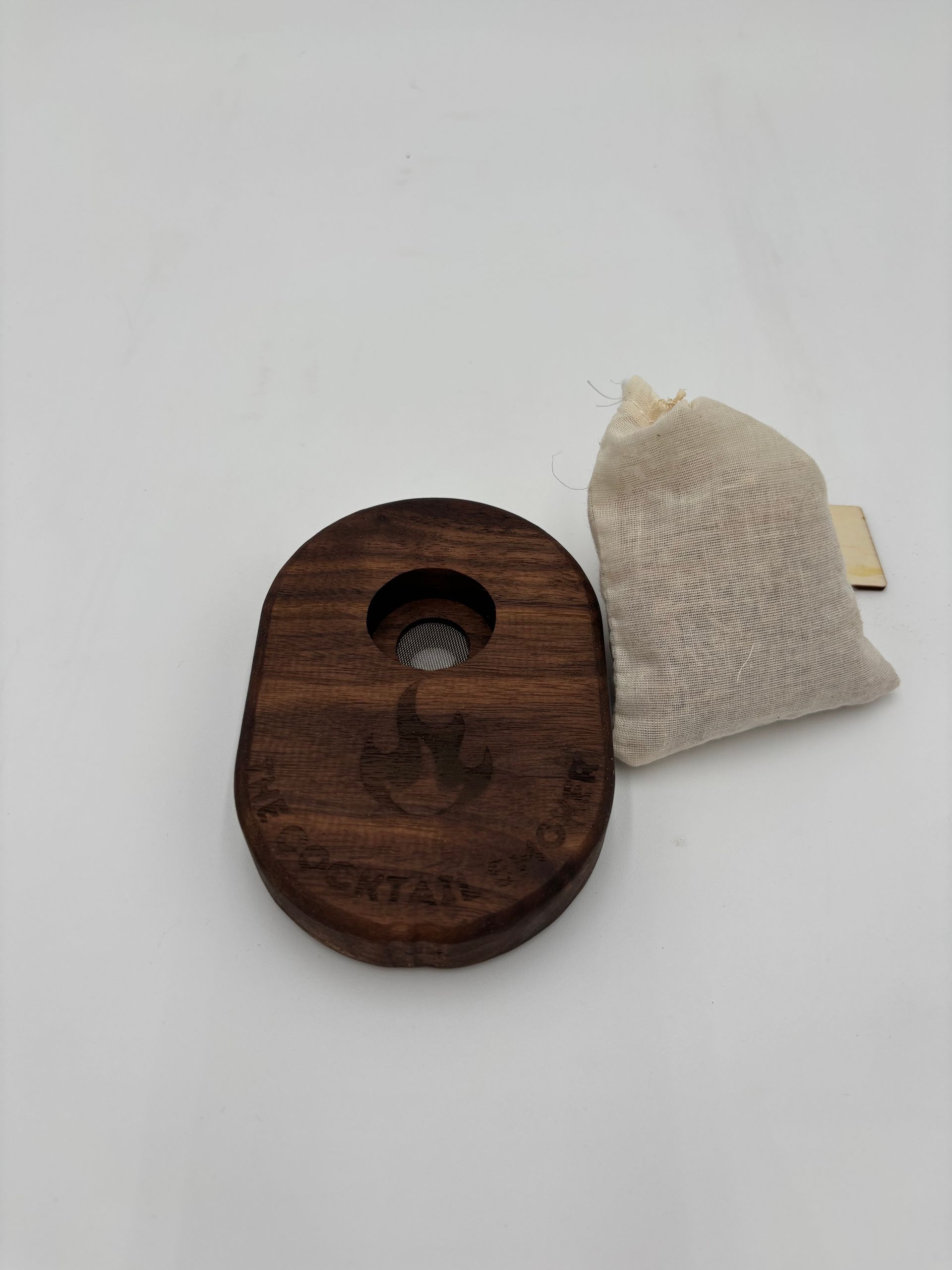 Wooden incense holder with a small fabric bag on a white surface.
