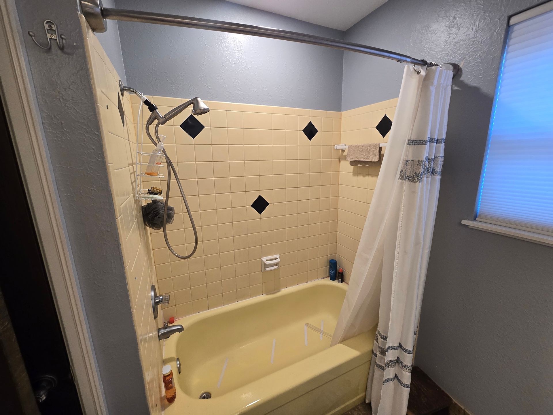 A bathroom with a bathtub , shower , and window.