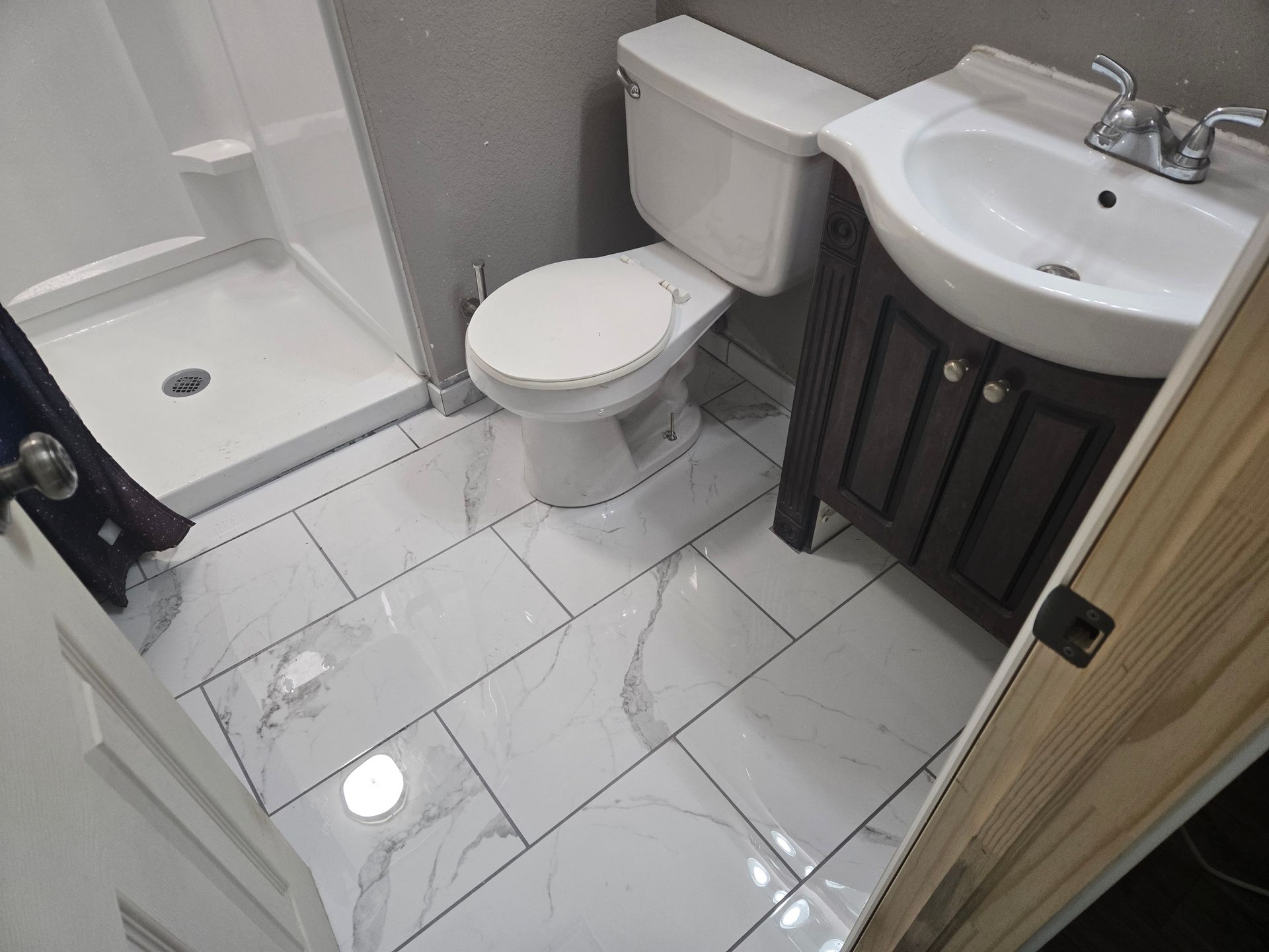 A bathroom with a toilet , sink and shower.