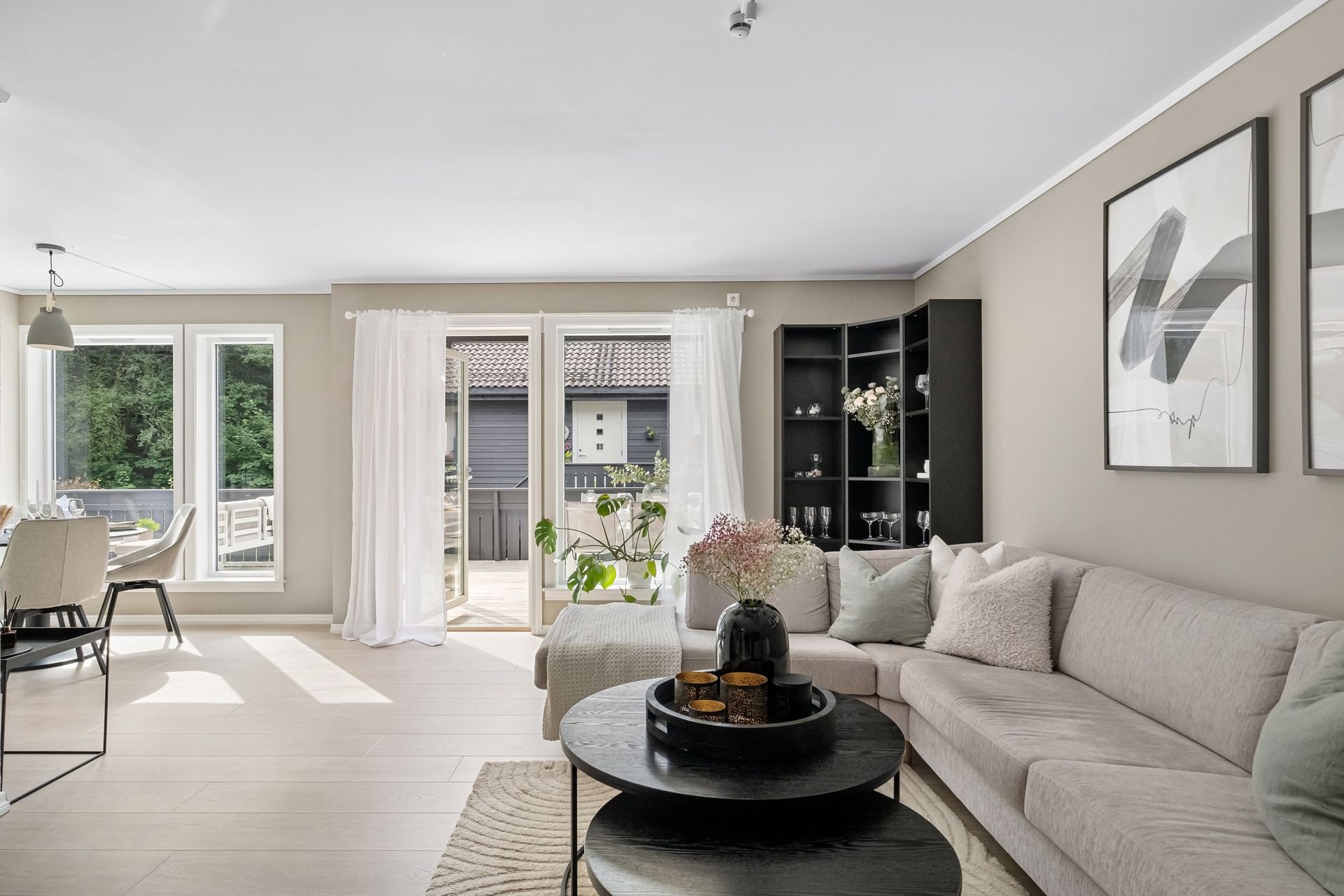 Bright living room with beige sectional, round black coffee table, and sliding glass doors to a balcony.
