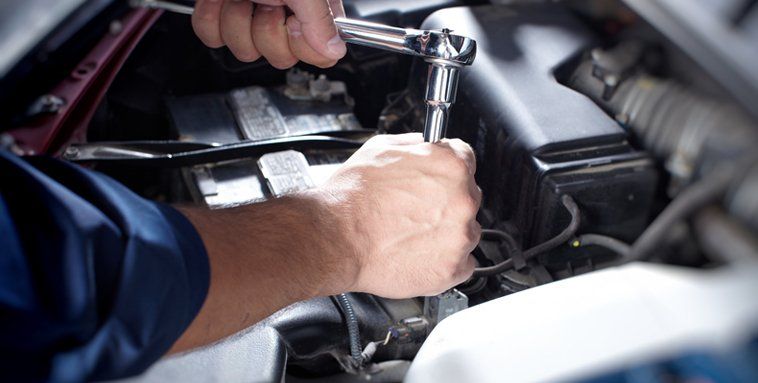 technician using a torque wrench on a car battery