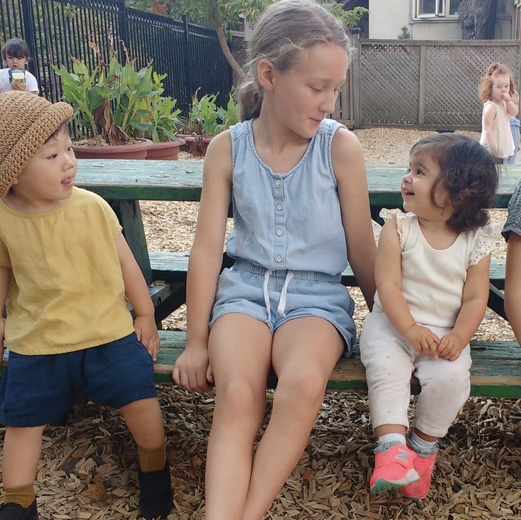 Montessori toddlers interacting with older child