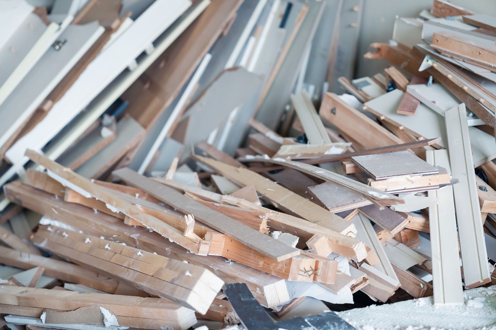 A cluttered pile of wooden construction debris, including scattered planks, boards, and pieces of furniture.