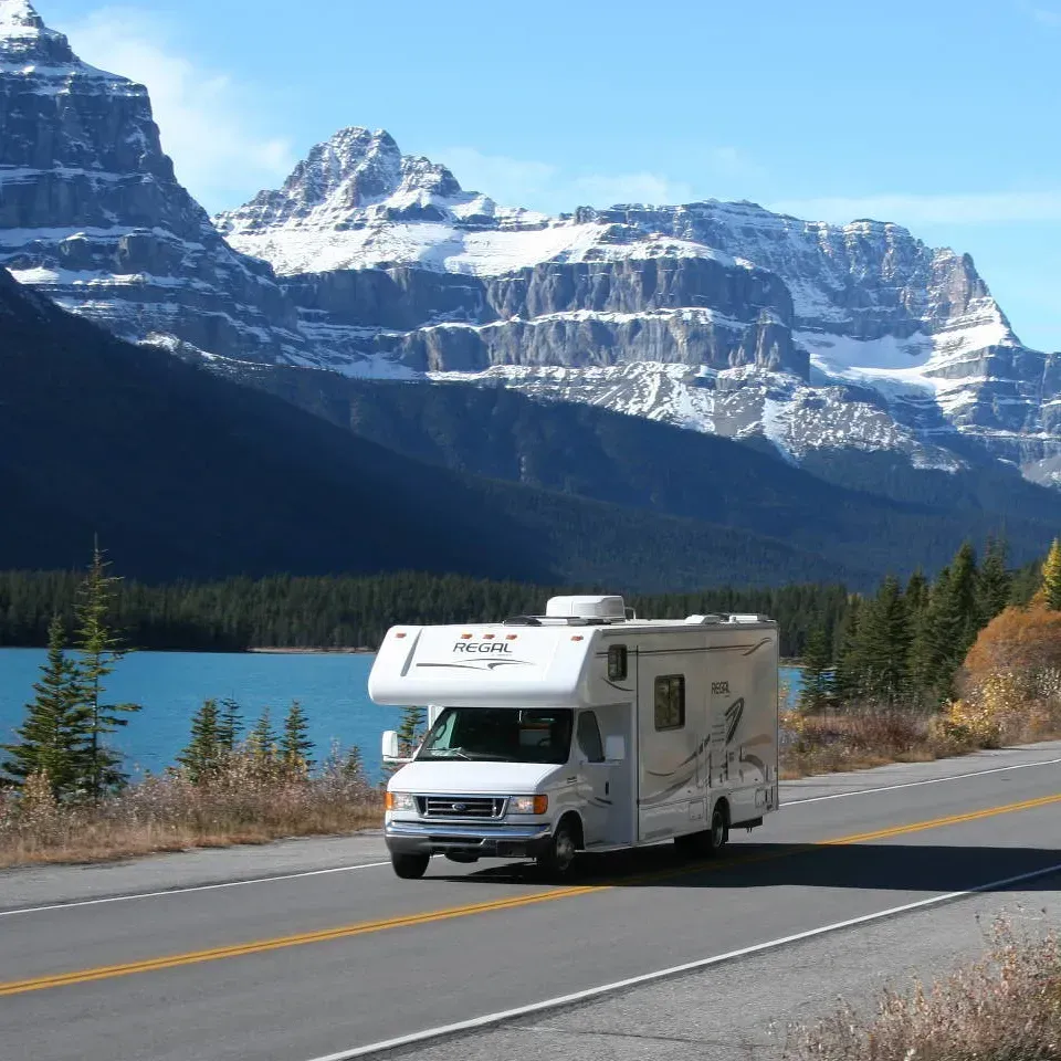 Ein Wohnmobil fährt eine Straße entlang, im Hintergrund sind Berge zu sehen