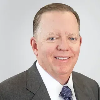 A man in a suit and tie is smiling for the camera.