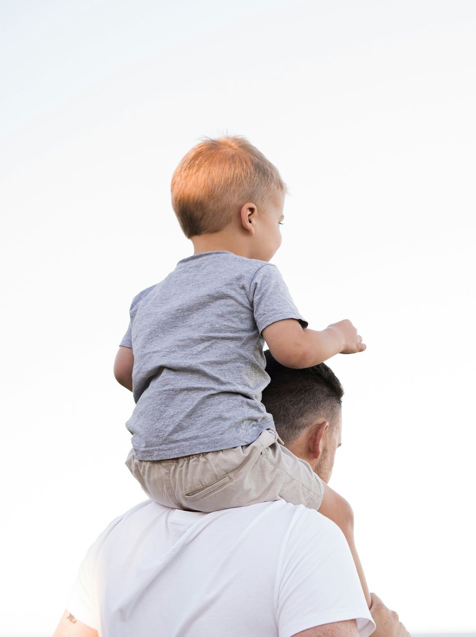 A man is carrying a little boy on his shoulders.