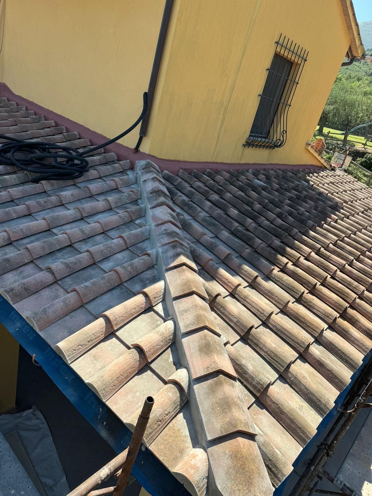 Un primo piano di un tetto di tegole con un edificio giallo sullo sfondo.