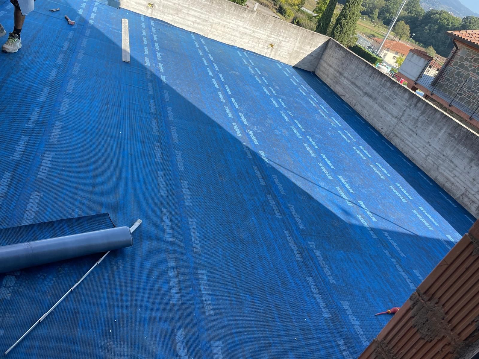 Un telo blu viene arrotolato su un tetto