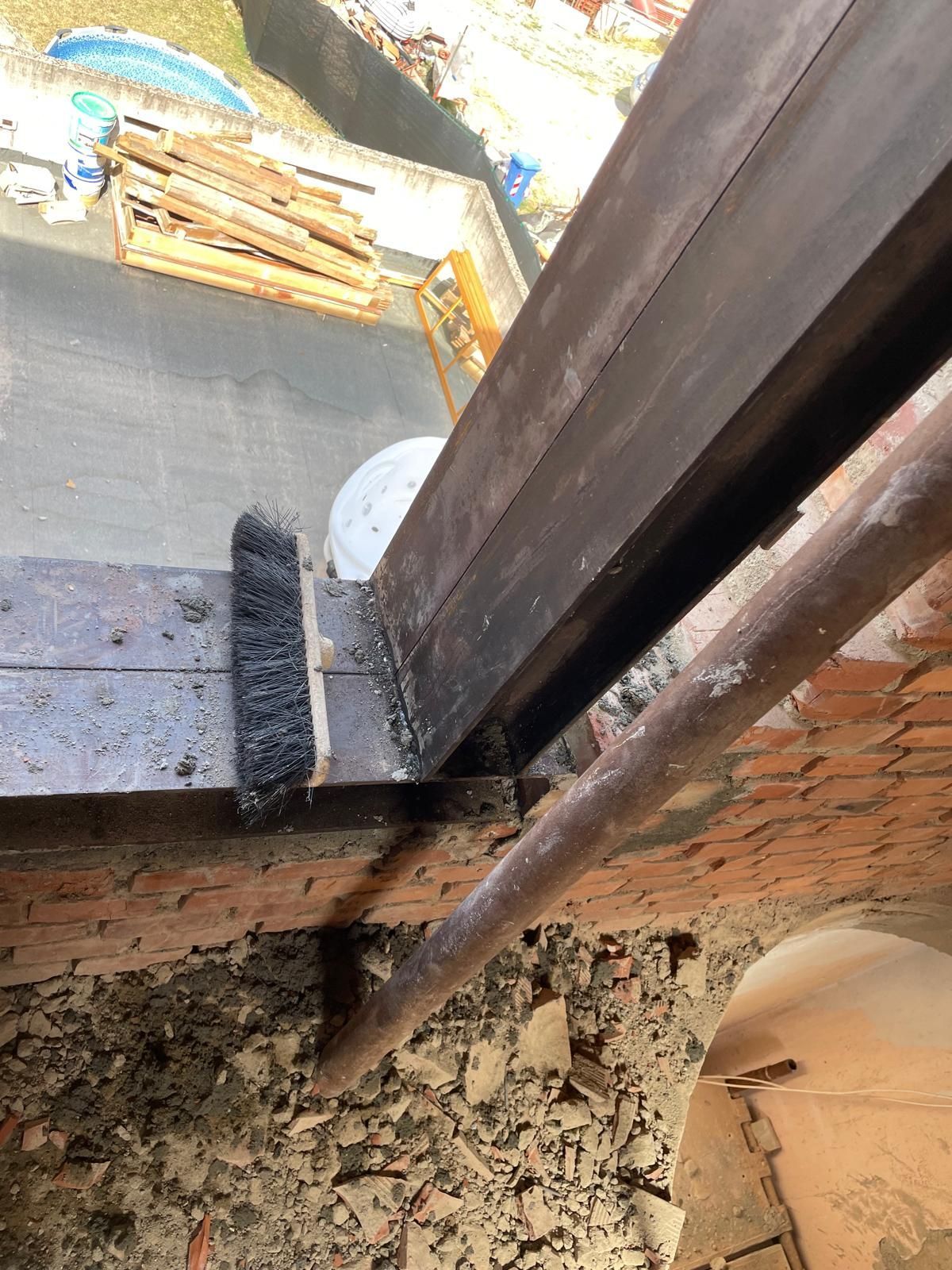 Una spazzola è appoggiata su un pezzo di legno accanto a un tubo.