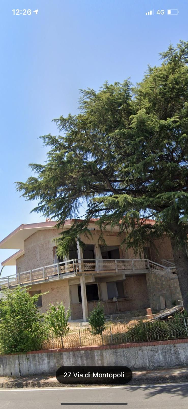 Una grande casa con un grande albero di fronte.