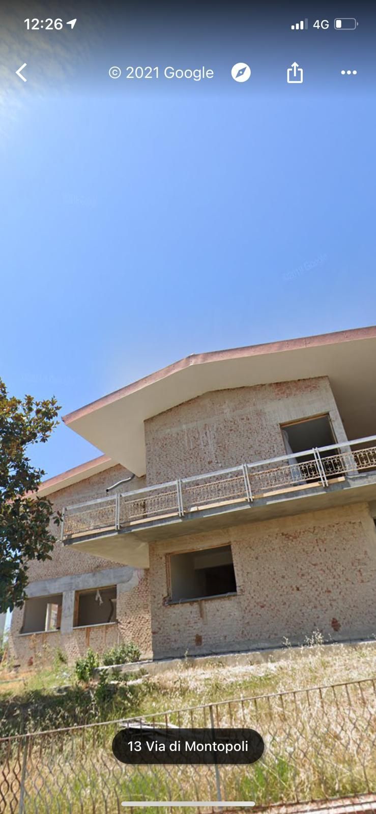 Una grande casa con un balcone si trova in cima a una collina.
