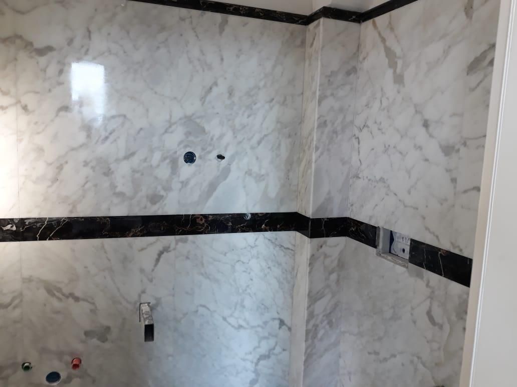 Un bagno con pareti in marmo bianco e finiture nere.