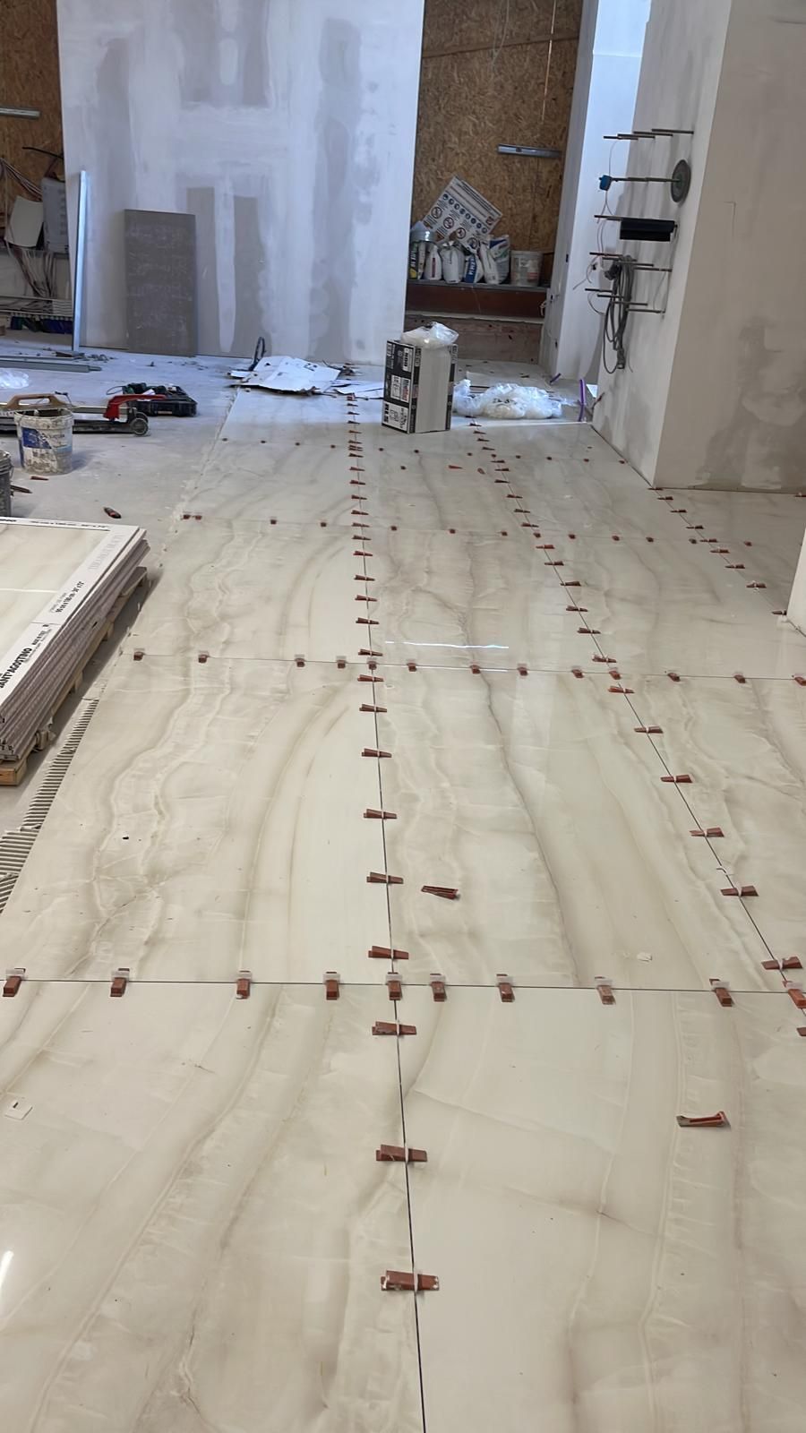 In una stanza viene installato un pavimento in piastrelle bianche.