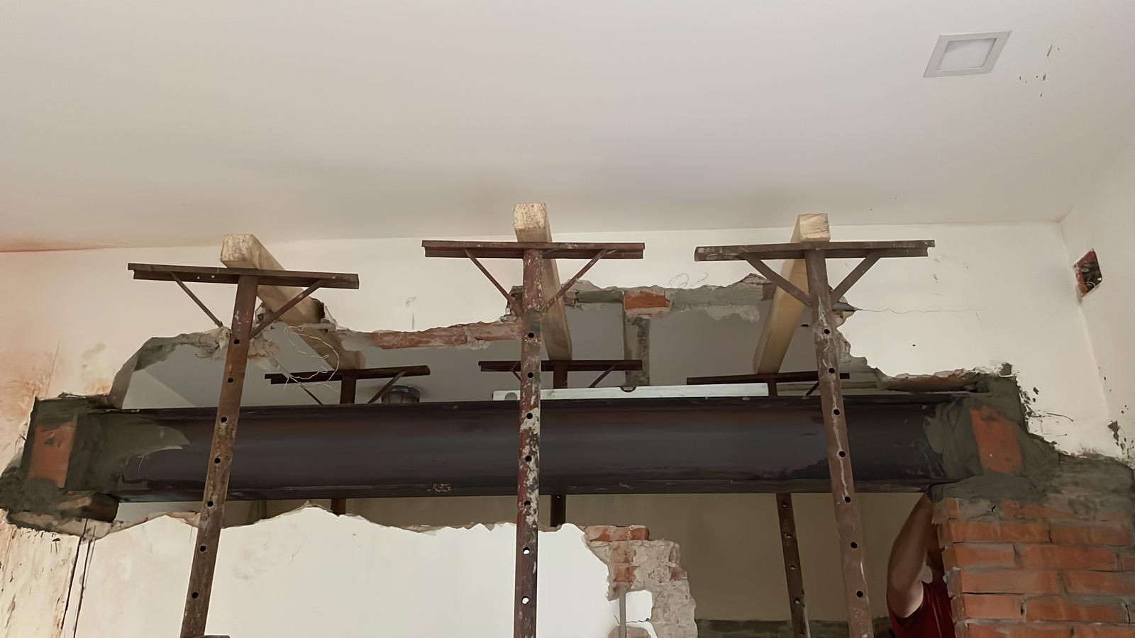 Una trave metallica viene installata in un muro di mattoni.