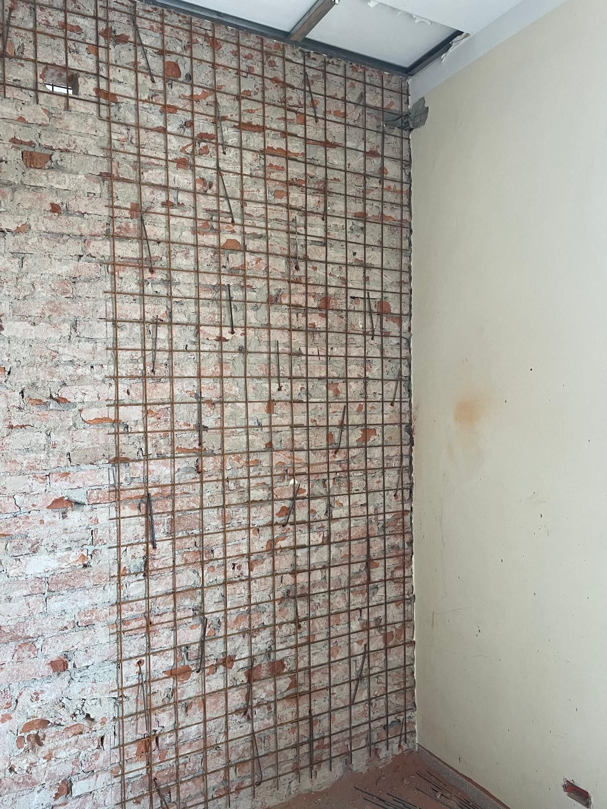 Una stanza con un muro di mattoni e una rete metallica.