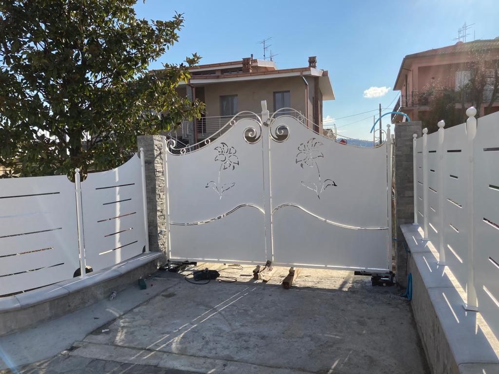 Un cancello bianco è aperto su un vialetto di fronte a una casa