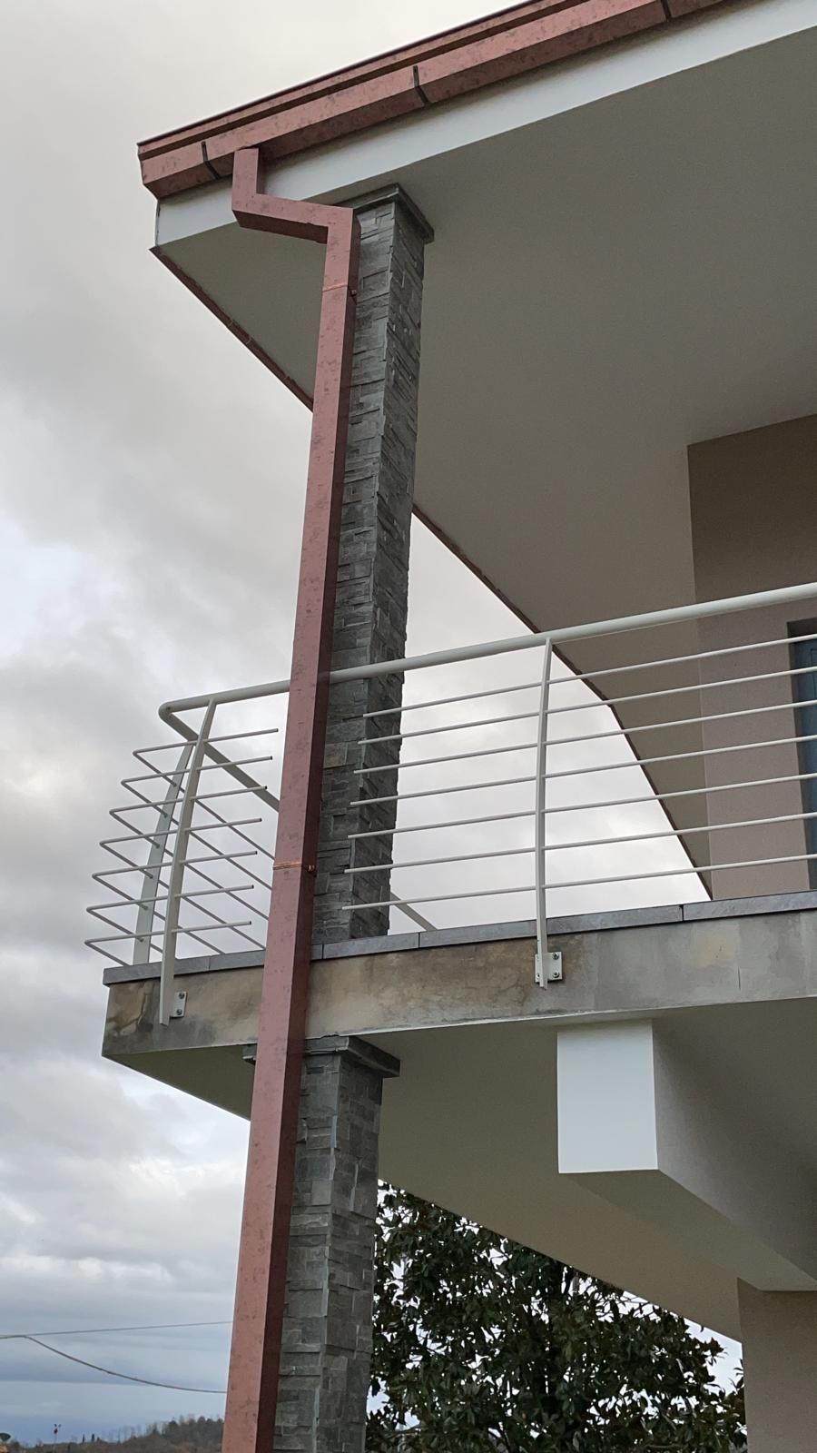 Un balcone con ringhiera metallica e grondaia sul lato di un edificio