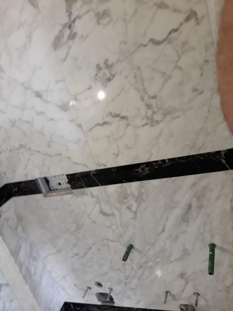 Una persona è in piedi in un bagno con una parete di marmo.