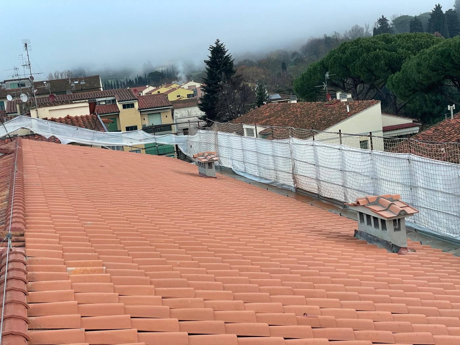 Un tetto di tegole rosse con un camino in cima.