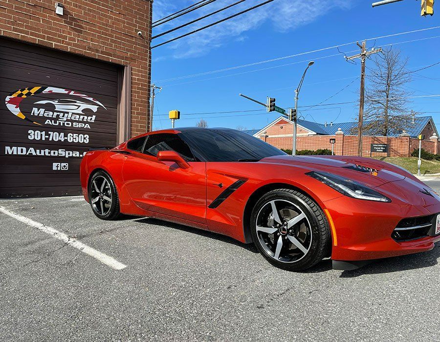 A red sports car is parked in front of a garage.