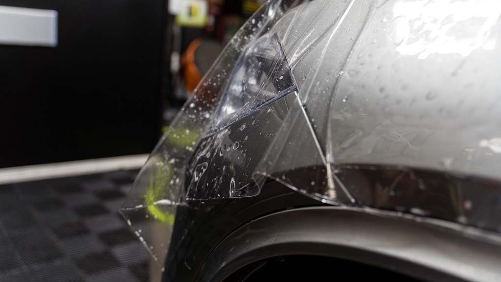 A close up of a car fender with a clear film on it.