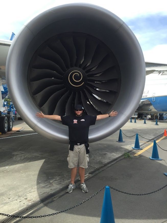 Carson Mangum posing next to a jet engine during the Air Force One detailing event at the Museum of Flight