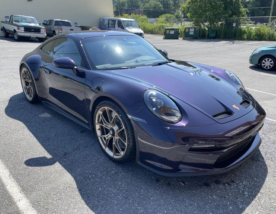 A purple porsche 911 is parked in a parking lot.