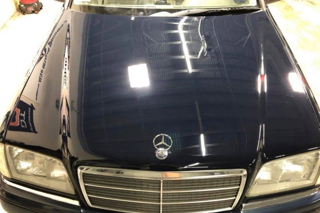 A black mercedes benz is parked in a garage.