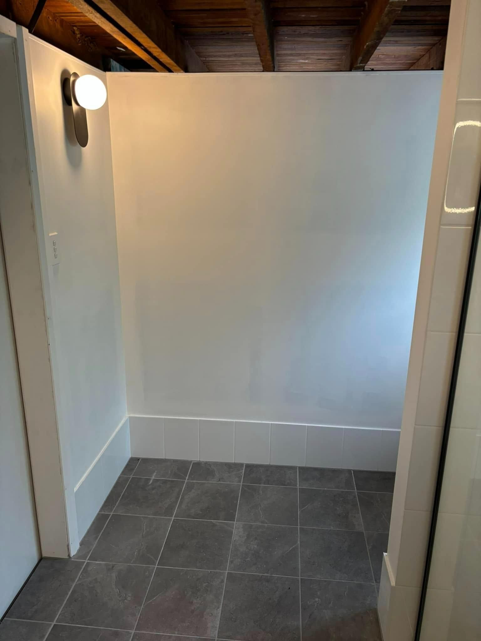 A Bathroom with A Tiled Floor and A White Wall — Polson Construction in Kedron, QLD