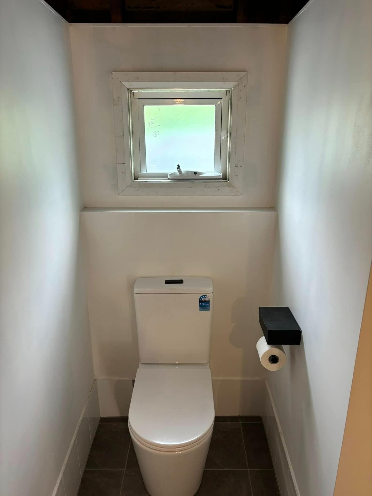 A Small Bathroom with A Toilet and A Window — Polson Construction in Kedron, QLD