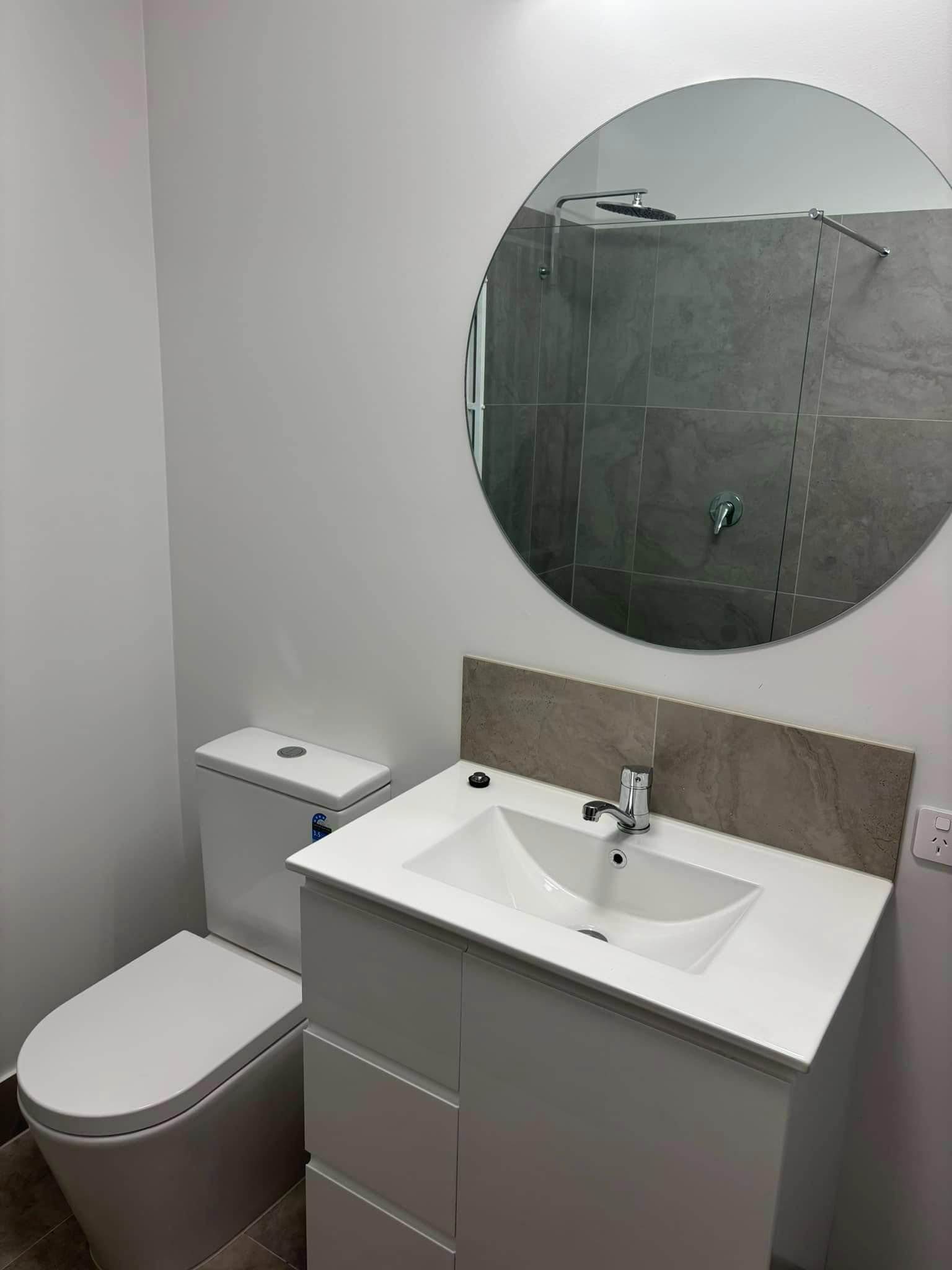 A Bathroom with A Toilet, Sink, and Mirror — Polson Construction in Kedron, QLD